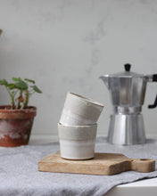 Load image into Gallery viewer, Stack of ceramic cups on a wooden cutting board with a metal coffee percolator in the background.